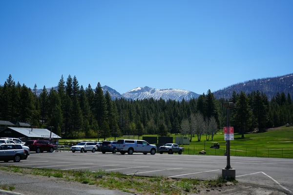 Mountain parking lot with snow-capped peaks and pine trees
