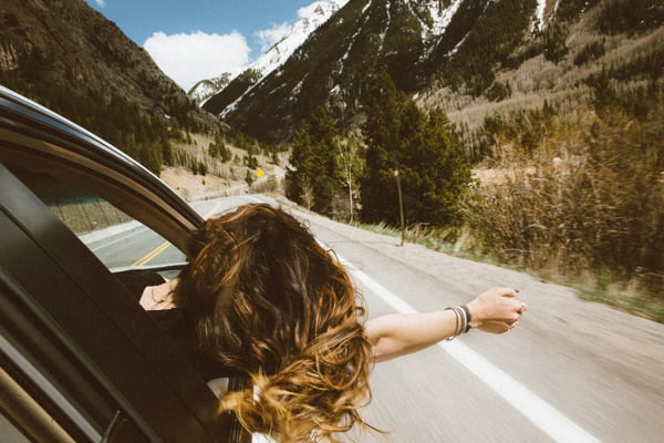 Woman leaning out of car window on a mountain highway