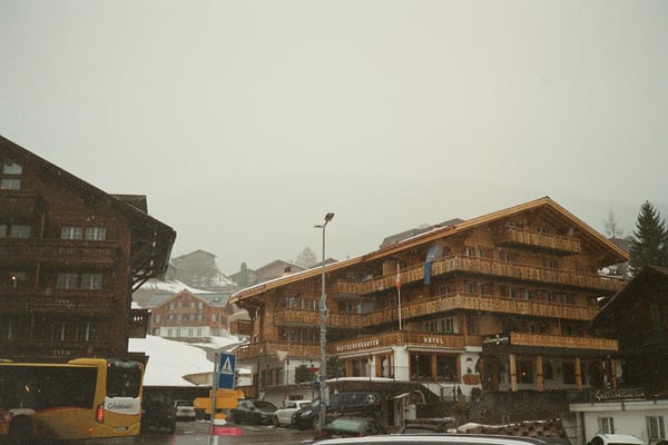 Snowy mountain village with parked cars and wooden buildings