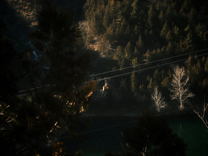 Zipline rider over forest and mountain lake