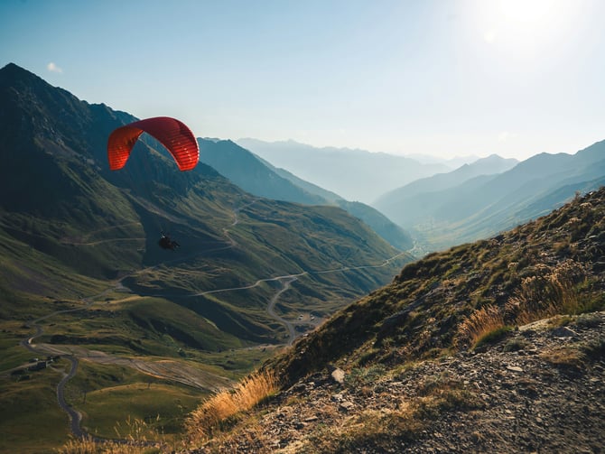 Paraglider soaring over a sunny mountain valley