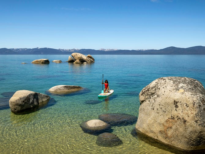 Paddleboarder on a clear blue mountain lake