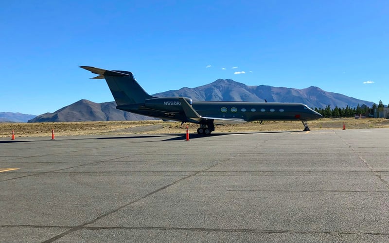 Private jet on mountain airport tarmac with peaks in background