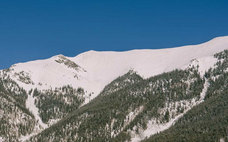 Ski slope with skiers and mountain village in winter